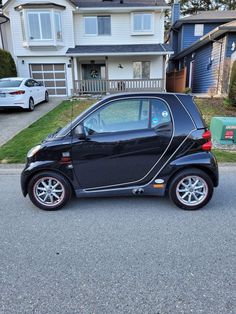 a small black car parked in front of a house