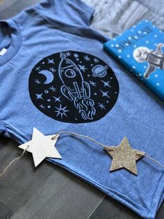 a t - shirt with an image of a rocket ship and stars on it