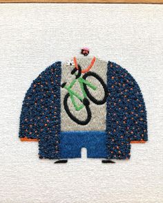 a close up of a piece of cloth with a bicycle on it and an orange, white, and blue design