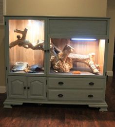 a cabinet with some animals in it on top of a hard wood floor next to a wall