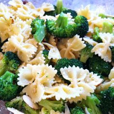 pasta and broccoli are mixed together in a glass bowl on top of a table