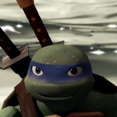 the teenaged ninja turtle is holding two swords in his right hand and looking at the camera