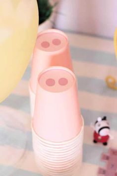 three pink plastic cups sitting on top of a table next to a toy panda bear