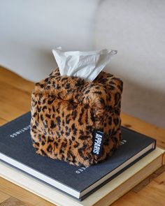 a tissue dispenser sitting on top of a book that is covered in leopard print