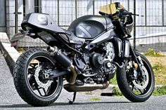 a black motorcycle parked on the street next to a fence