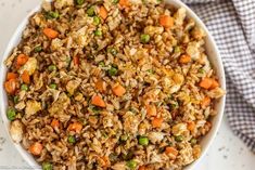 a bowl filled with rice and vegetables on top of a white tablecloth next to a blue checkered napkin