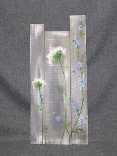 a piece of wood with flowers painted on it and some white fabric behind the painting