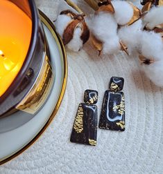 two black and gold earrings sitting next to cotton