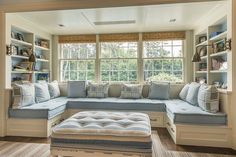 a living room filled with lots of furniture next to a window covered in bookshelves