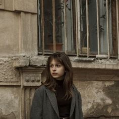 a woman standing in front of an old building with bars on the window sill