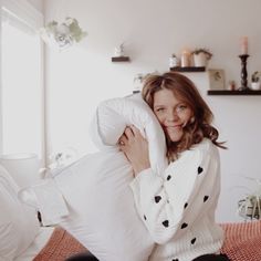 a woman sitting on a bed holding a pillow