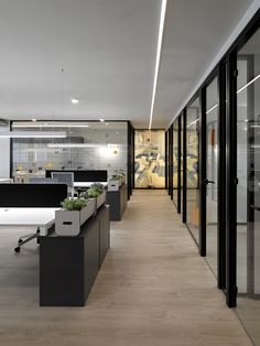 an empty office with desks and planters in the center, along with glass walls