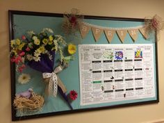 a bulletin board with flowers and bunting on the wall next to a bird nest