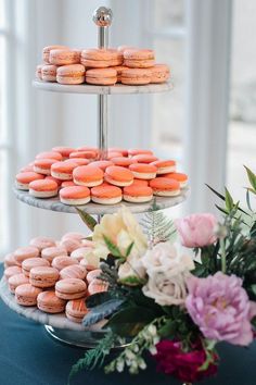 three tiered trays filled with pink and orange macaroons on a blue table cloth