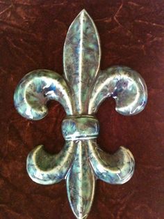 a metal fleur de lis on a brown surface