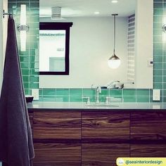 a bathroom with green tiled walls and wooden cabinetry on the vanity, along with a large mirror