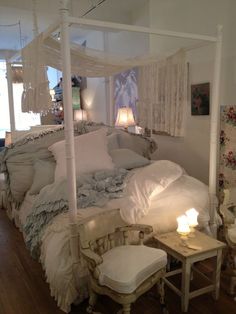 a white bed sitting on top of a wooden floor next to a table and chair