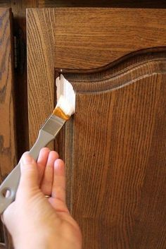 someone using a paint brush to apply wood grain on a cabinet door with an adhesive tape