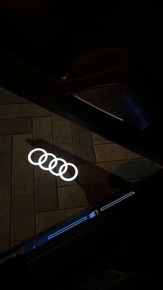 an illuminated sticker on the ground next to a laptop and cell phone in the dark