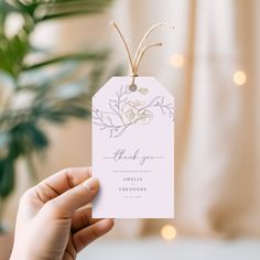 a person holding up a white tag with flowers on it