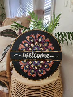 a welcome sign sitting on top of a wicker basket next to a potted plant