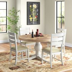 a dining room table with chairs and a rug on the floor