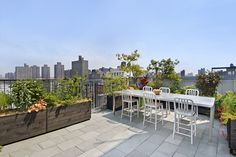 an outdoor dining table and chairs on a roof deck with city skyline in the background