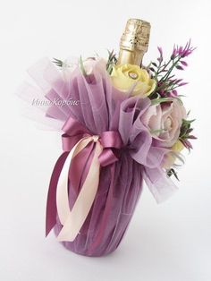 a bottle of champagne and some flowers in a purple basket on a white tablecloth