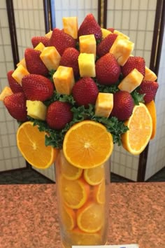 a vase filled with oranges and strawberries on top of a counter next to a sign