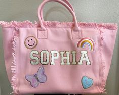 a pink handbag with embroidered name and pictures on the front, sitting on top of a chair