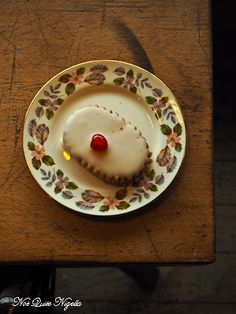 a white plate with a piece of cake on it sitting on top of a wooden table