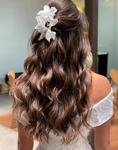 the back of a woman's head with long, wavy hair and a flower in her hair