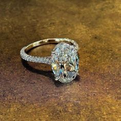 an oval cut diamond ring sitting on top of a table