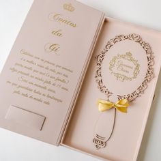 an open pink box with a gold bow on the front and back of it's lid