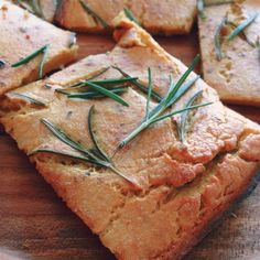 slices of bread with rosemary sprigs on them sitting on a cutting board, ready to be eaten