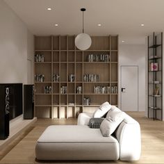 a white couch sitting in front of a wooden book shelf filled with lots of books