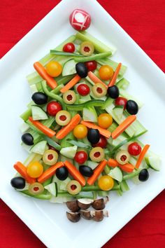 a white plate topped with cucumbers, carrots and olives on top of lettuce