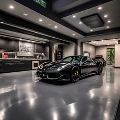 a black sports car is parked in a large room with dark cabinets and lights on the ceiling