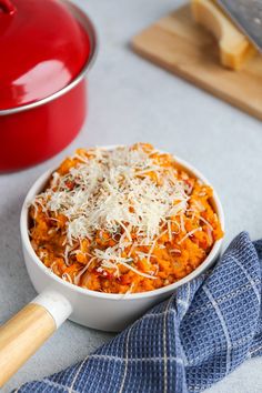 a white bowl filled with pasta and parmesan cheese on top of a blue towel