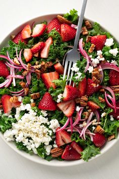 a salad with strawberries, feta cheese and pecans is shown in a bowl