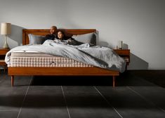 a man and woman laying on a bed in a room with black tile flooring