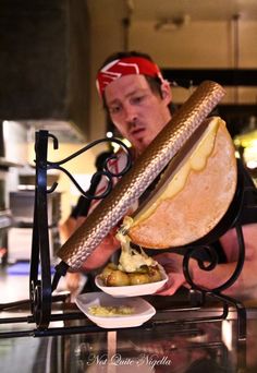 a man holding a giant sandwich on top of a plate next to a bowl of food