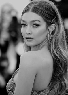 a woman with long hair wearing earrings and posing for the camera in black and white