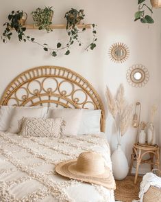 a bed with white sheets and pillows in a bedroom next to plants on the wall