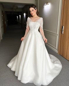 a woman in a white wedding dress standing on the floor with her hands behind her back