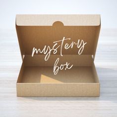 an open box with the words mystery box written in white on it, sitting on a wooden surface