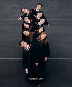 a group of people in graduation gowns standing on top of a tennis court with their arms around each other