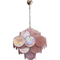 a pink chandelier hanging from a chain with coins in the center and angel wings on it