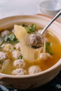 a spoonful of soup with meatballs and broccoli is being held up