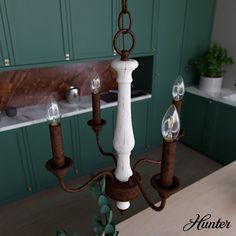 a white chandelier hanging from a wooden table in a green and brown kitchen